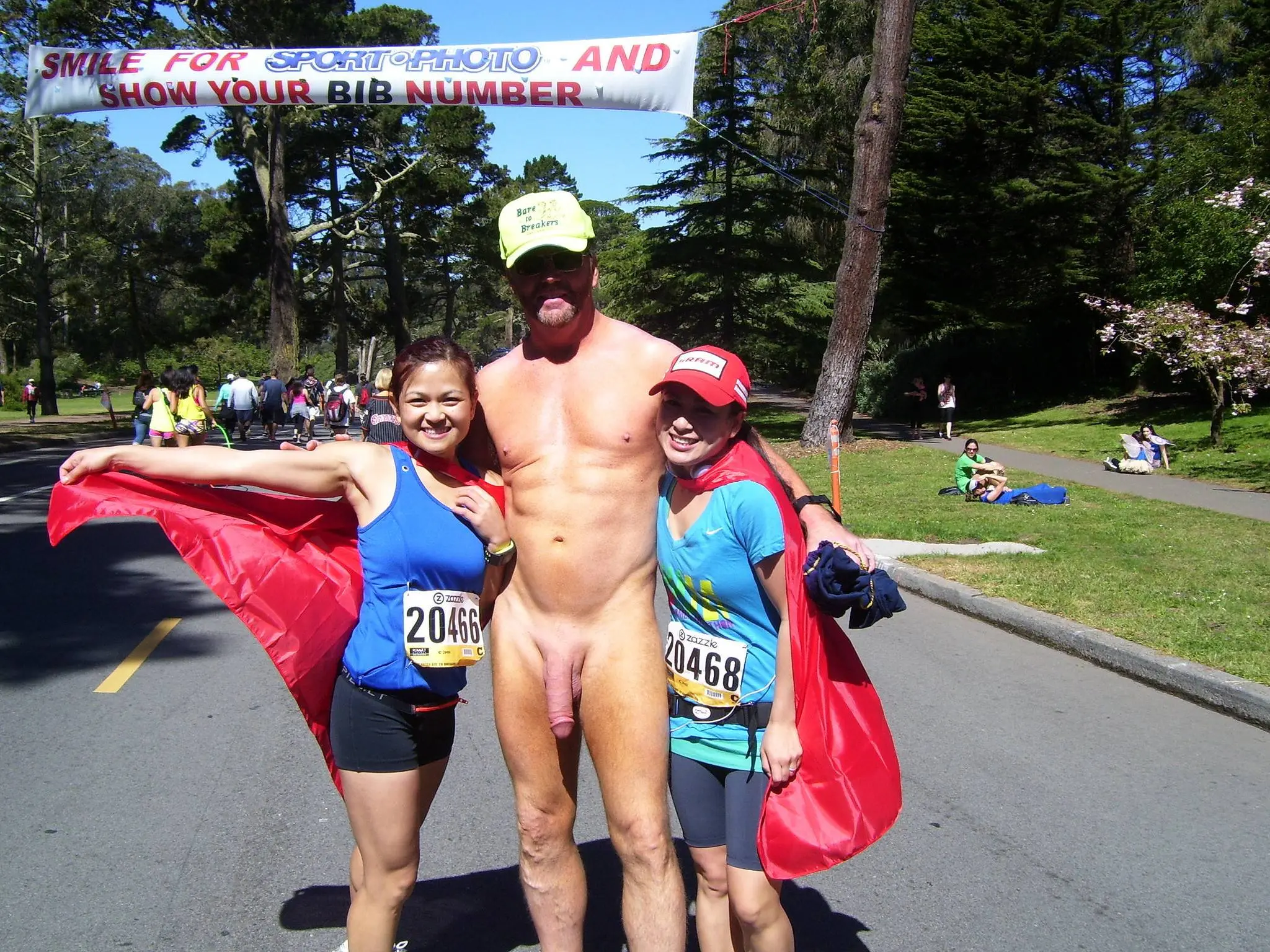Hung white man posing nude with women in costumes at Bay to Breakers street fair, CFNM public exhibitionism