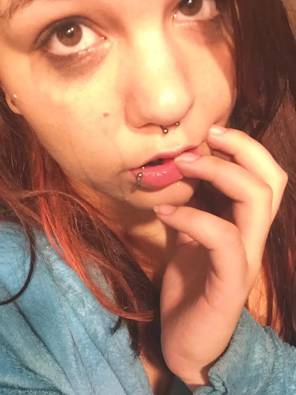 Slim white redhead with piercings in a blue robe, topless and posing with a purple object for blacktears