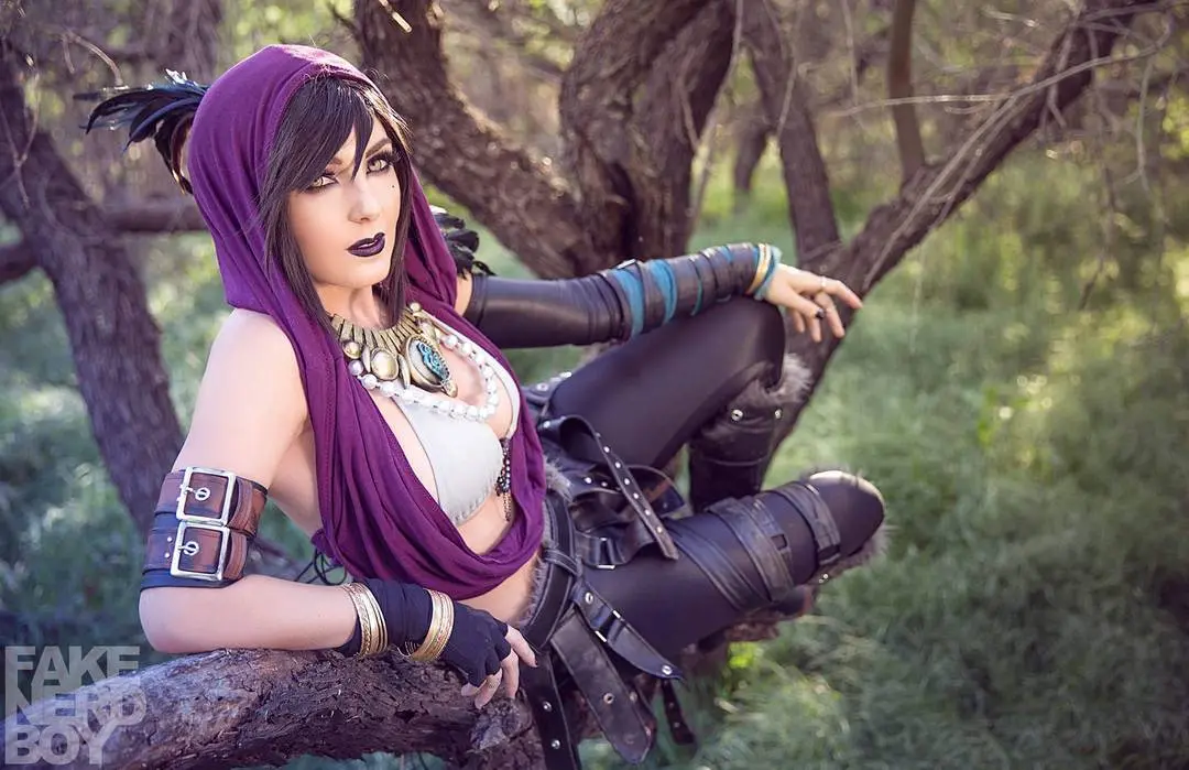 Jessica Nigri in a purple Ifrit cosplay, wearing a white bikini top and black leggings, sitting on a tree branch.