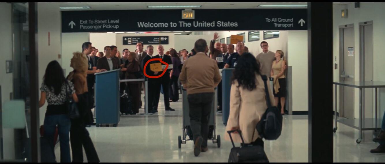 Inception ending airport scene,there is a guy holding an orange placard ...