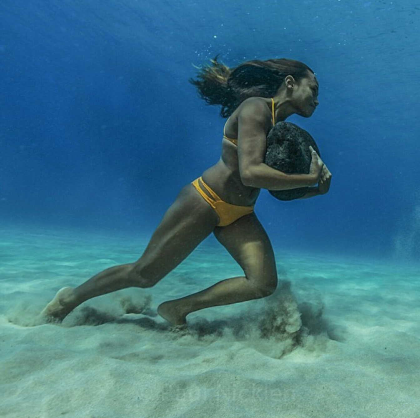 Hawaiian surfer Ha’a Keaulana runs across the ocean floor with a 50 pound boulder, as training to survive the massive surf waves