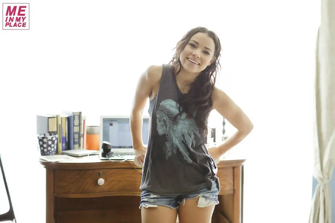 Jessica Parker Kenney in tank tops and denim shorts posing in a New York City living room and bathroom