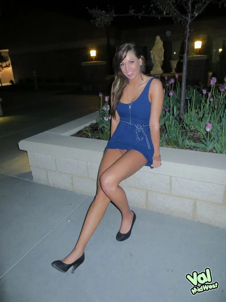 Val theWoo in a blue mini dress posing topless and lying in a garden planter at night