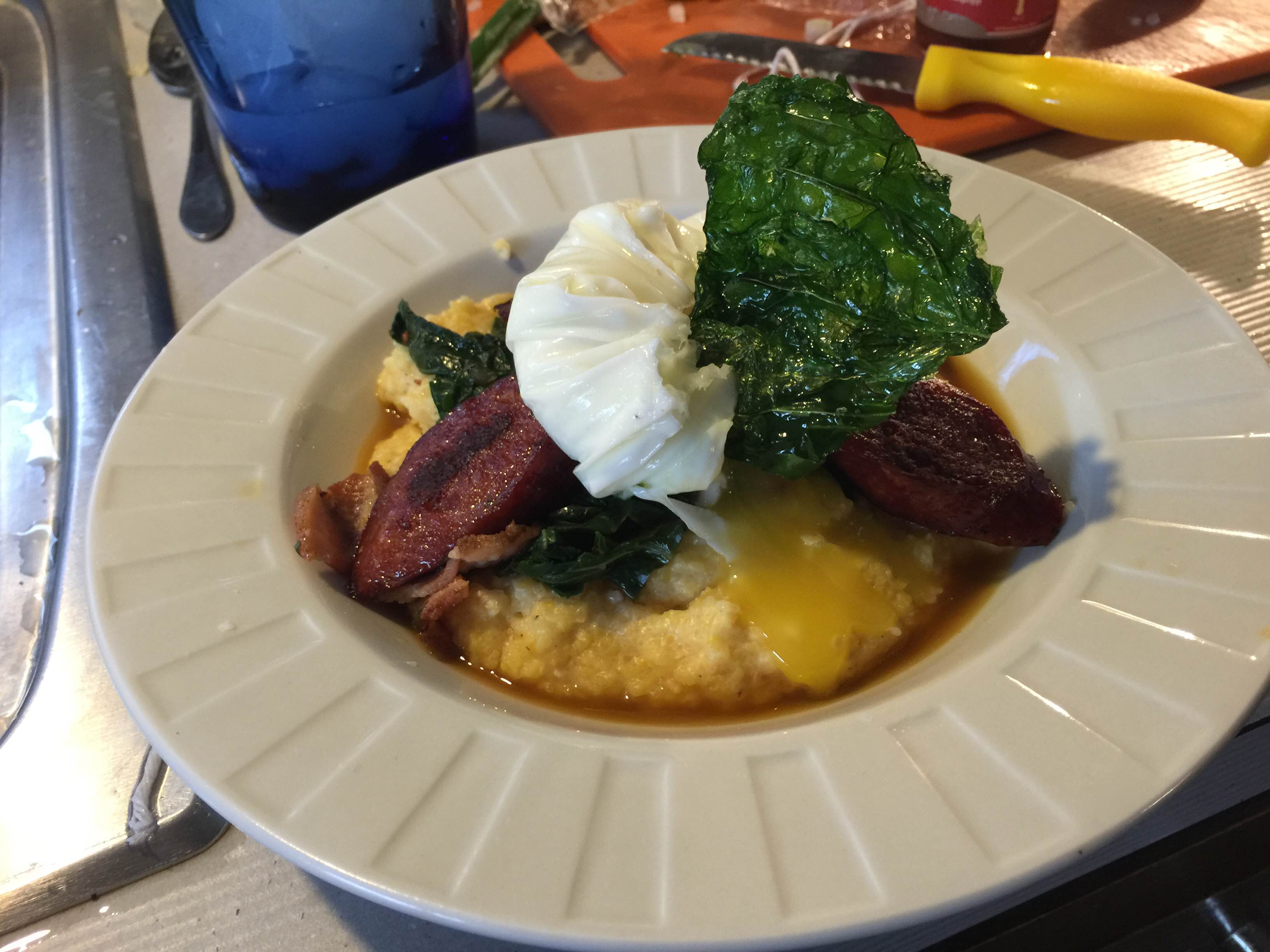 White cheddar grits, Andouille sausage, braised collards, Arzak egg, and a collard green chip