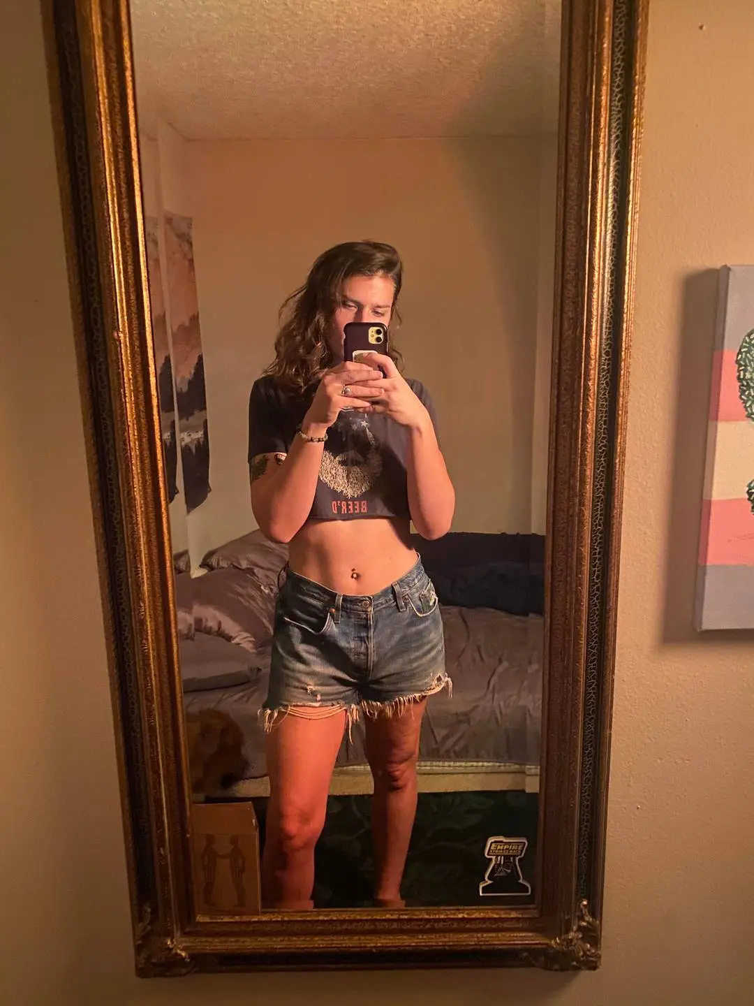 Transadorable girl next door taking a mirror selfie in a cropped dark t-shirt and denim shorts