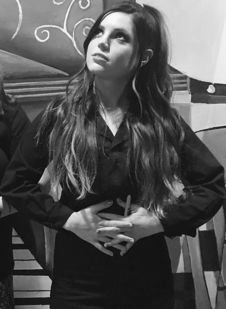 Sydney Sierota in a black and white fashion shot wearing a dark goth outfit with long wavy hair.