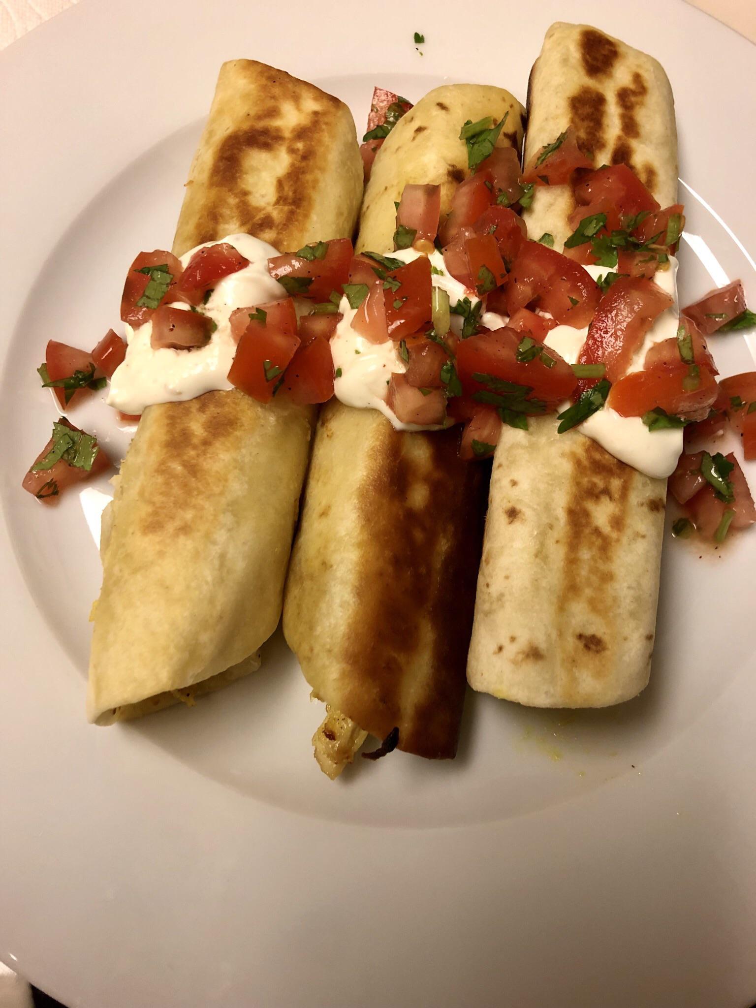 Chicken flautas with green chile sour cream and tomatocilantro topping