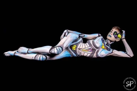 Emma Ruby in futuristic robot body paint lying on a black background