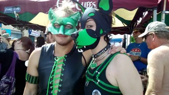 Kato and Pepper in pup play gear and masks at the Folsom Street Fair, including a man in a tiger costume.