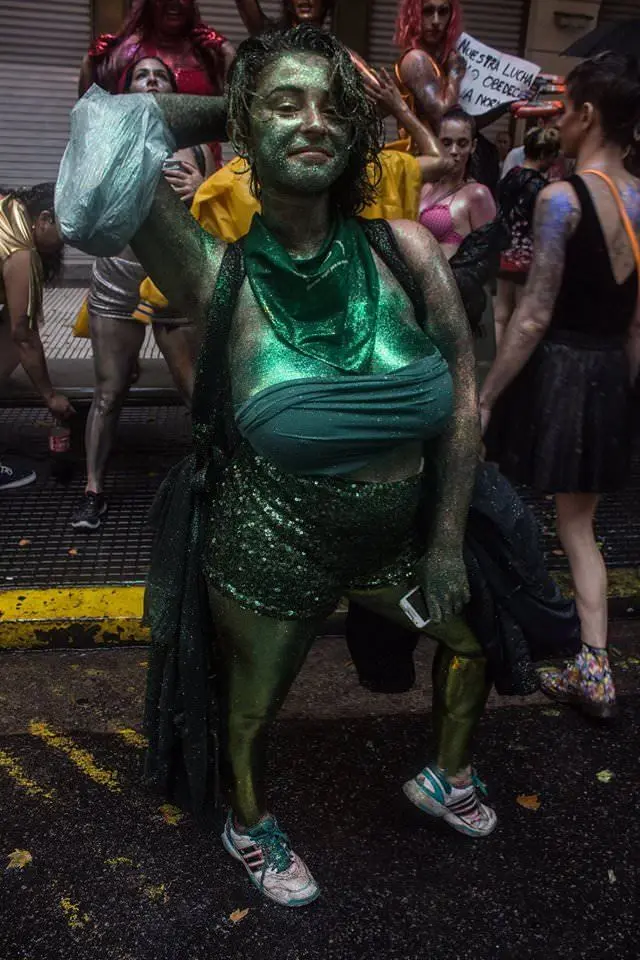 Athletic brunette woman in green goblin cosplay with body paint and glittery outfit