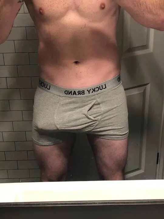 Mature white man with a tattoo and dad bod posing for a mirror selfie in grey CK boxer briefs showing a bulge