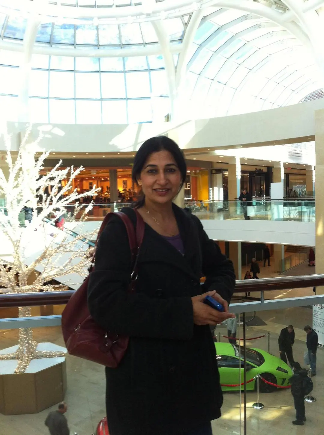 Slim Indian milf and bhabhi in a black coat and purple top smiling in a shopping mall