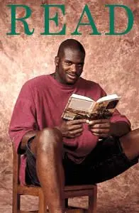 Shaq holding a book while sitting in a tiny chair
