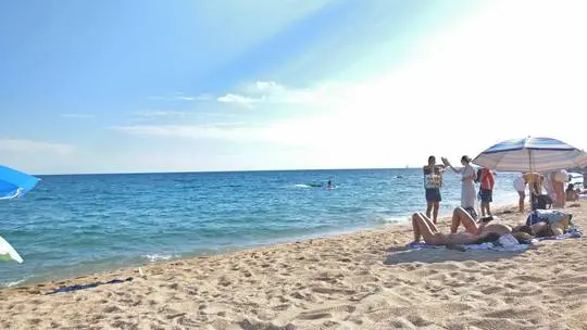 Naturist beach in Spain with slim white women in bikinis and summer dresses sunbathing by the ocean