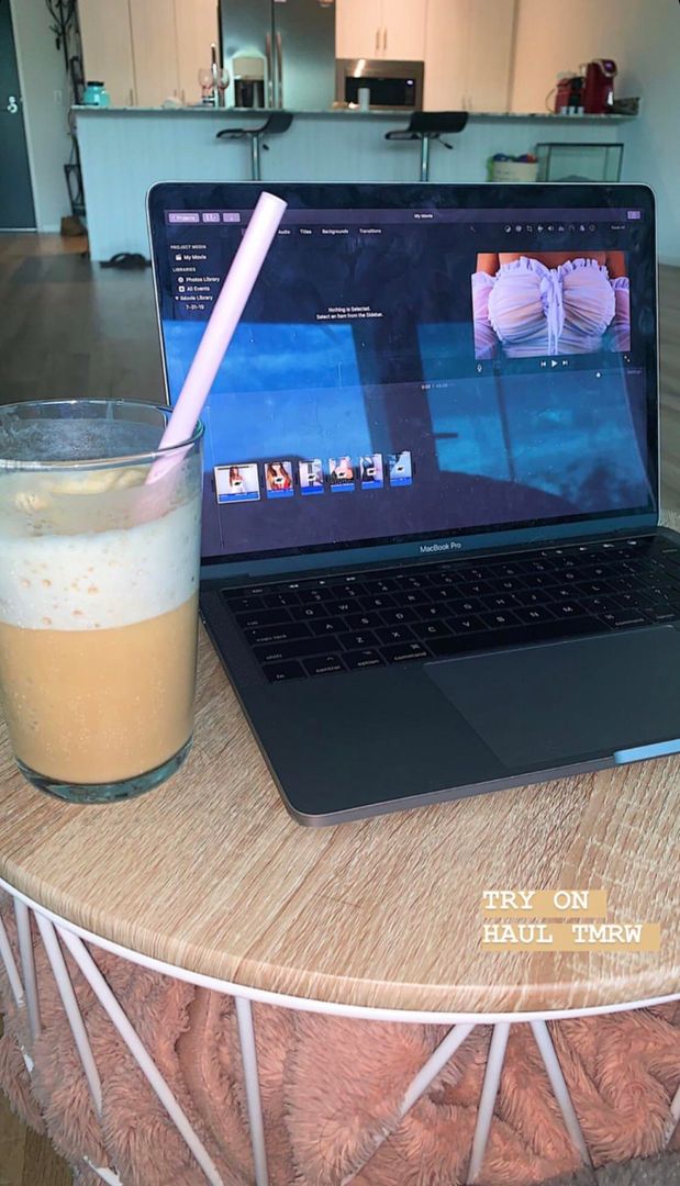 Taylor Alesia in a white corset posing for a try on haul video on a MacBook Pro screen