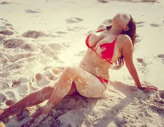 Curvy Indian bhabhi in a red bikini and turquoise sarong posing on a sandy beach