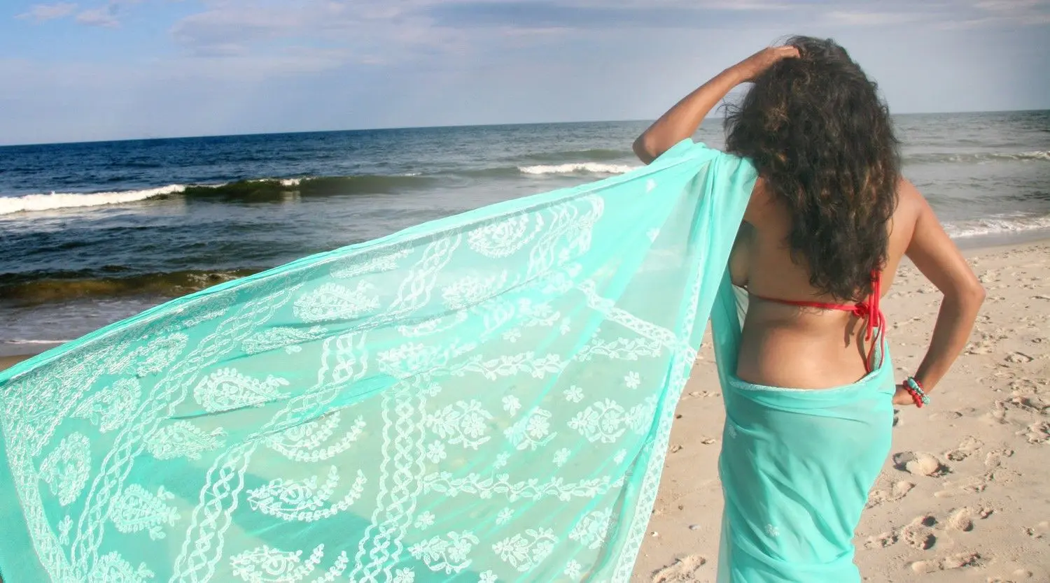 Curvy Indian bhabhi in a red bikini and turquoise sarong posing on a sandy beach