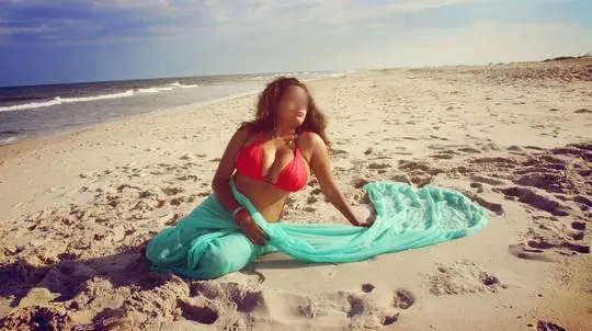 Curvy Indian bhabhi in a red bikini and turquoise sarong posing on a sandy beach