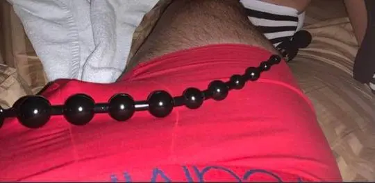 Athletic man in red underwear with anal beads inserted in a bedroom setting