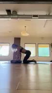 Athletic brunette woman in a black sports bra and leggings performing Mayurasana and yoga stretches in a studio