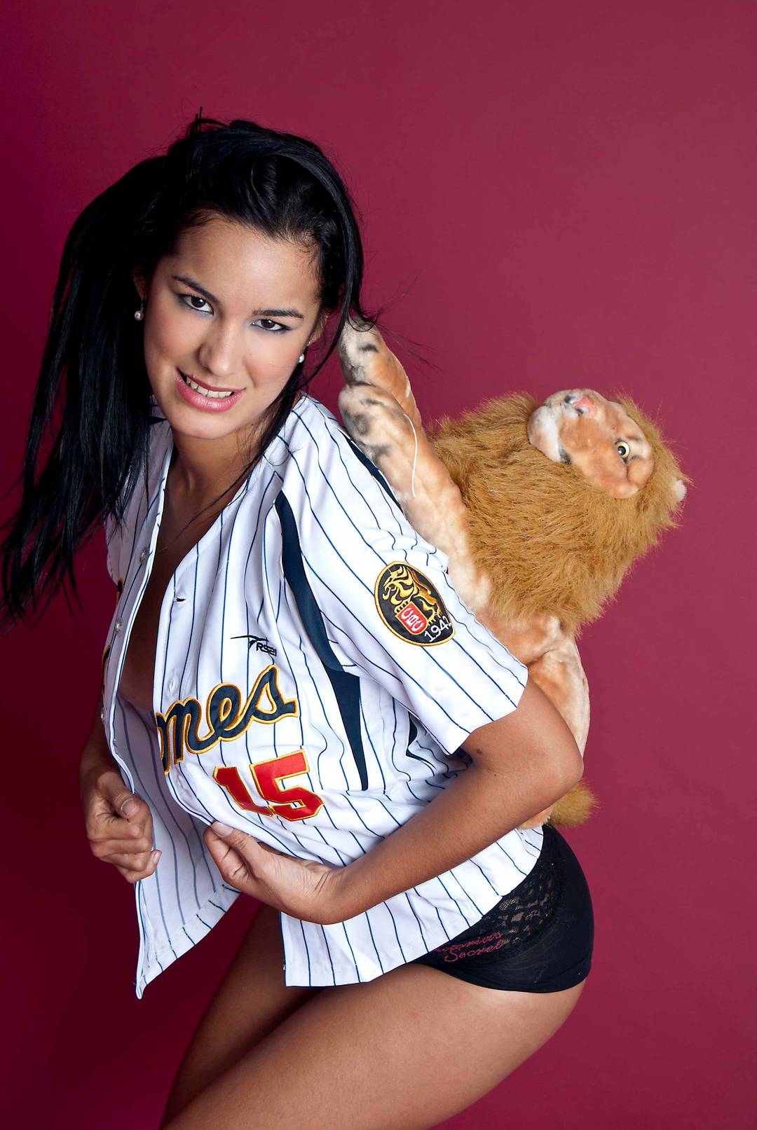 Edmar Leal posing in a baseball jersey, bra, and panties with a bat and glove in a studio