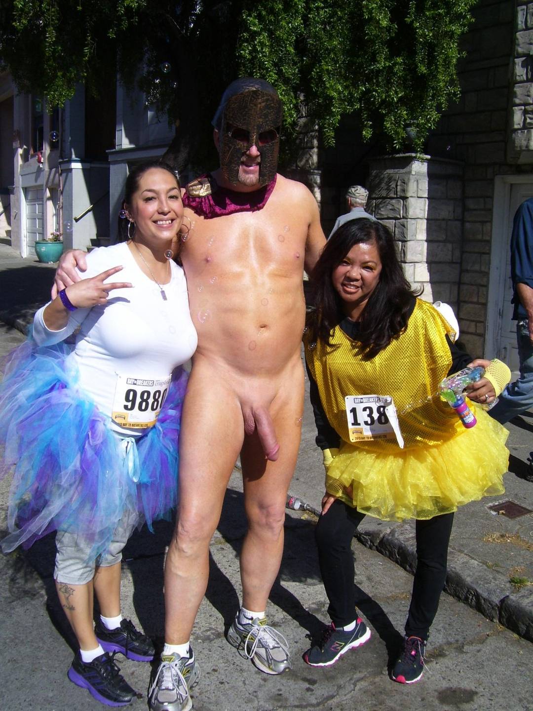Hung white man posing nude with women in costumes at Bay to Breakers street fair, CFNM public exhibitionism