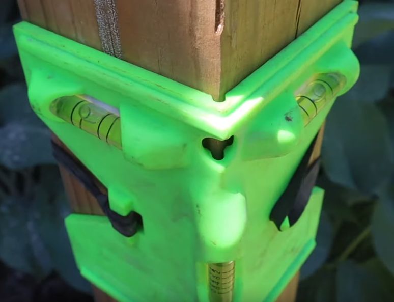 Fence post spirit level with elastic retainers.