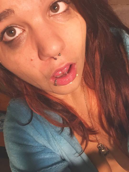 Slim white redhead with piercings in a blue robe, topless and posing with a purple object for blacktears