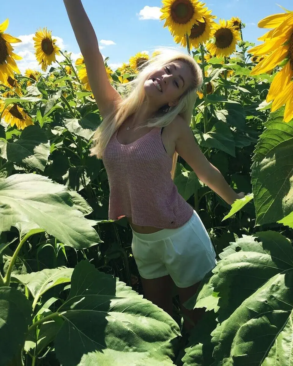 Dumb Blonde in a teal bikini on a boat, pink tank top in sunflowers, and a black crop top at Lollapalooza