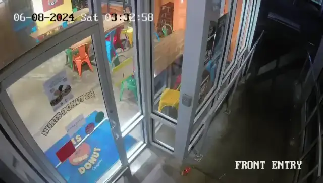 Shirtless athletic black man smashing a trash can against a Hunts Donut Co. glass door at night