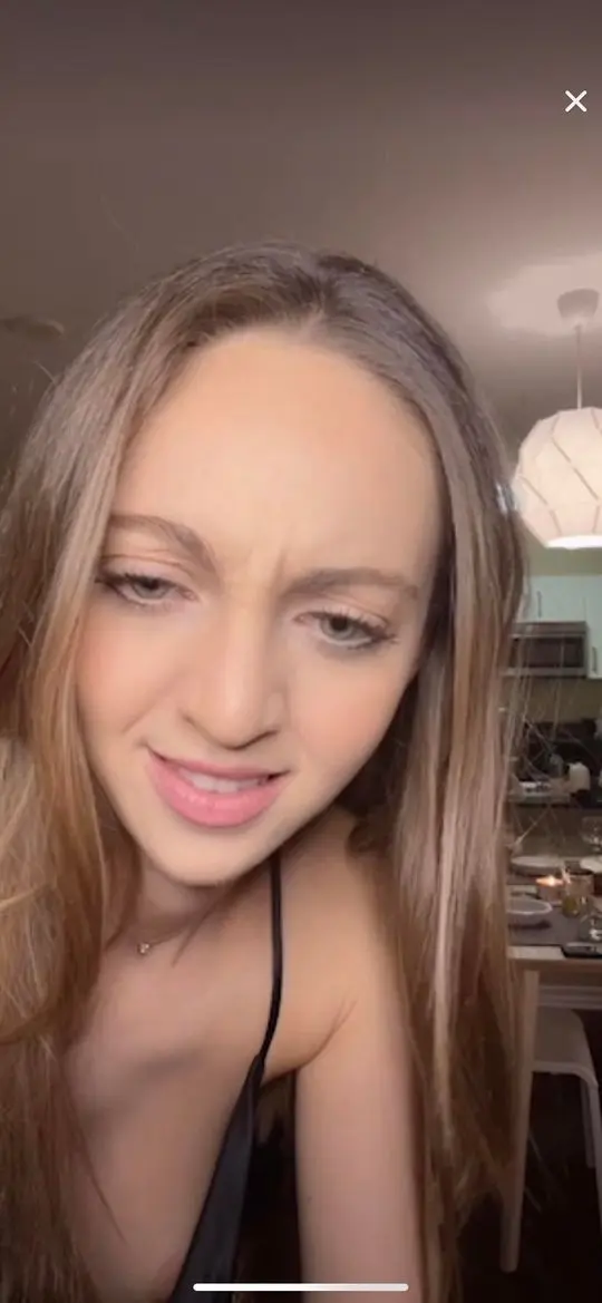 Tiktok live nip slip of a slim white woman with long brown hair making a funny face in a close-up selfie