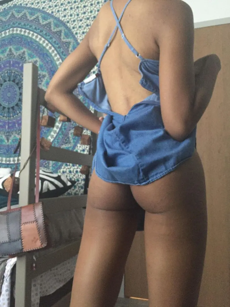 Ebony woman with a curvy body in a blue dress stripping in a bedroom selfie