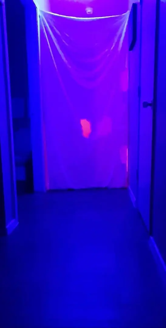 Gloryhole setup in an indoor room with purple and blue blacklight and a white fabric backdrop.