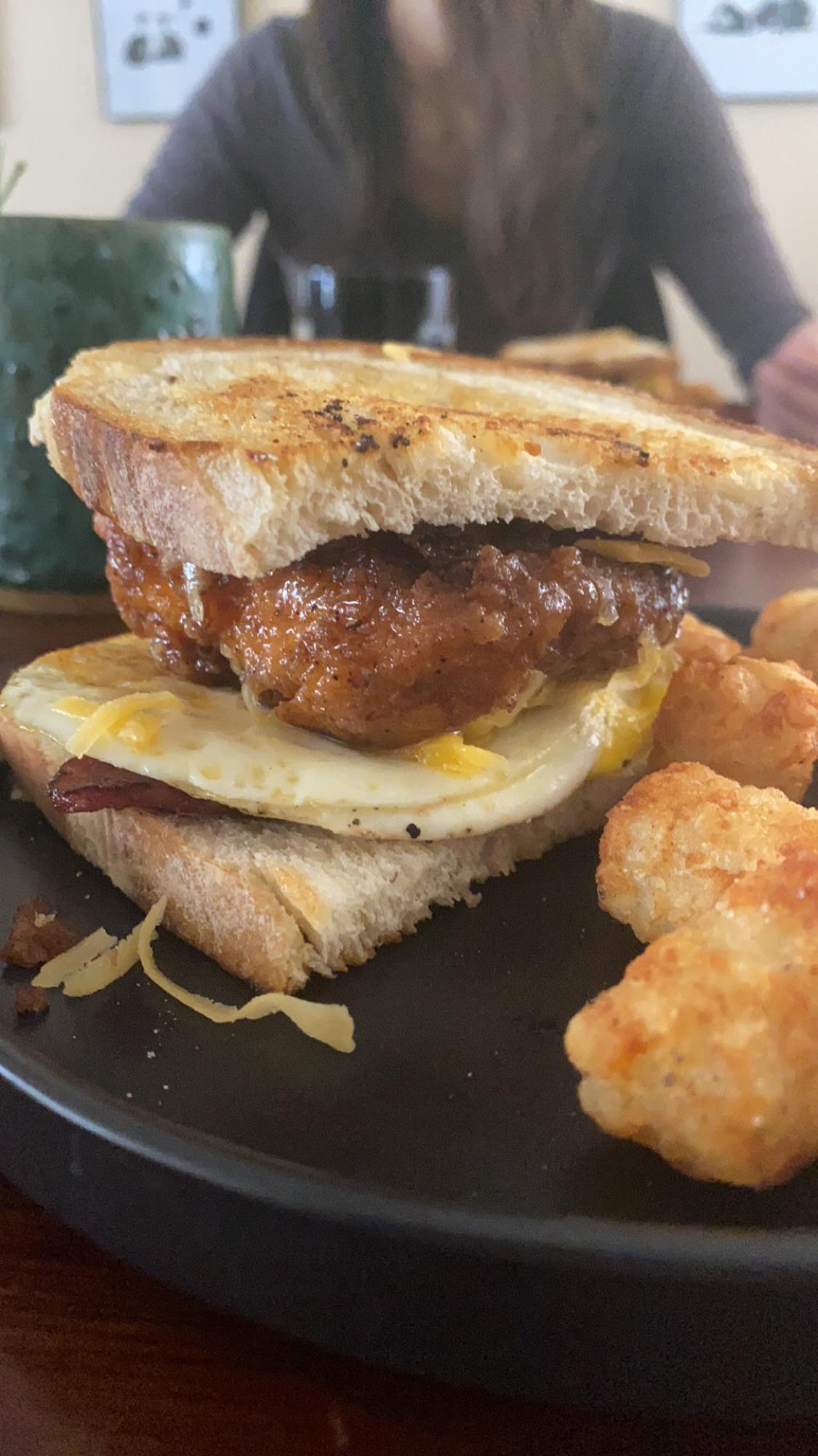 Buttermilk fried chicken with a fried egg, a slice of breakfast ham seared in butter, grated