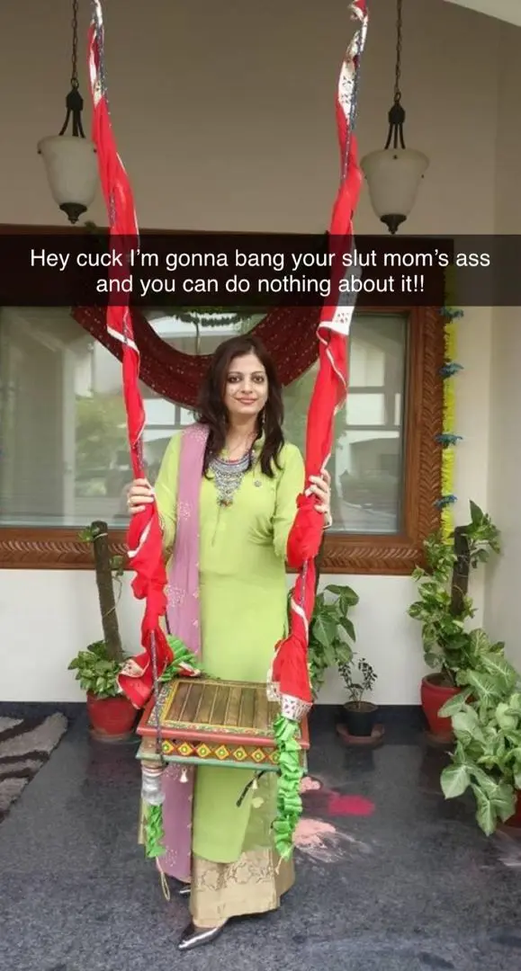 Mature Indian woman in a green salwar kameez and pink dupatta standing by a decorative swing