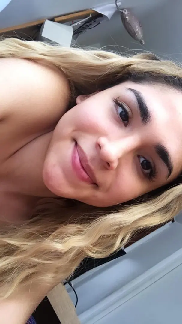 peruvianputa, a mixed woman with blonde wavy hair, smiling in a topless selfie