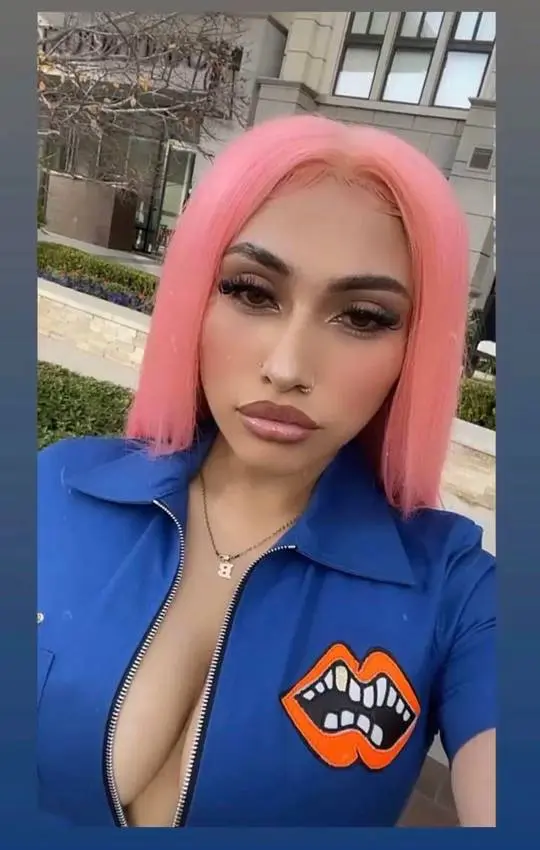 Brivnnna, a curvy Latina ABG with pink hair, wearing a blue zip-up shirt with a lip graphic.