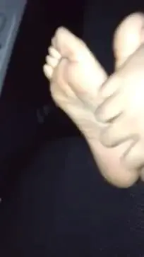 Slim blonde black woman showing her bare soles and toes in a car interior