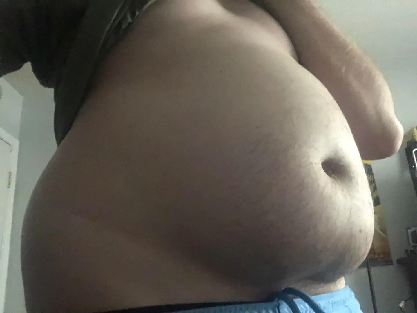 A close-up pelfie of a white man's fat belly and navel, wearing blue underwear.