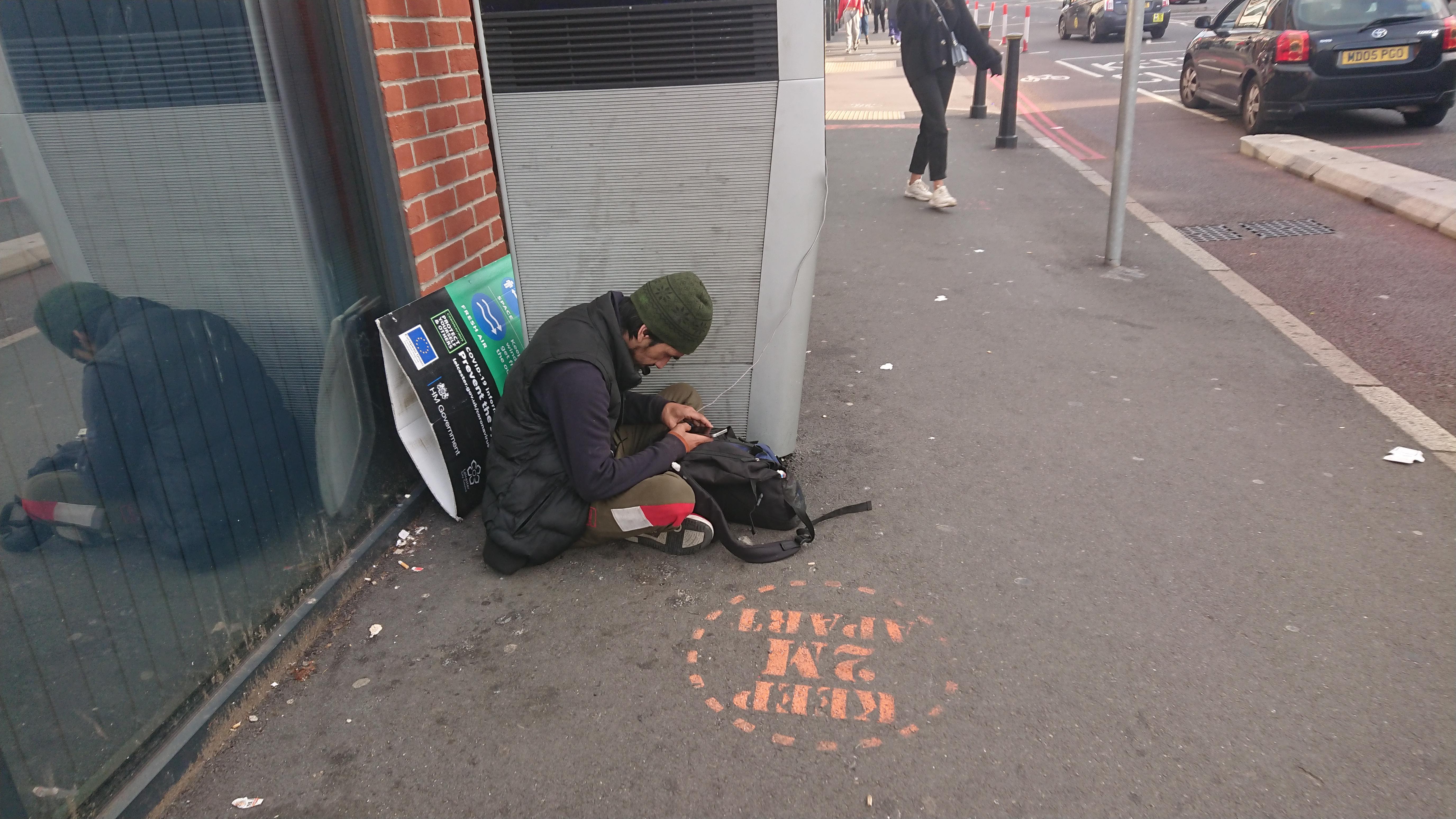 A homeless man charging his phone. Scrolller