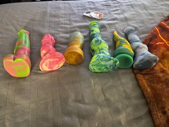 Bad Dragon fantasy dildos with colorful patterns on a grey surface