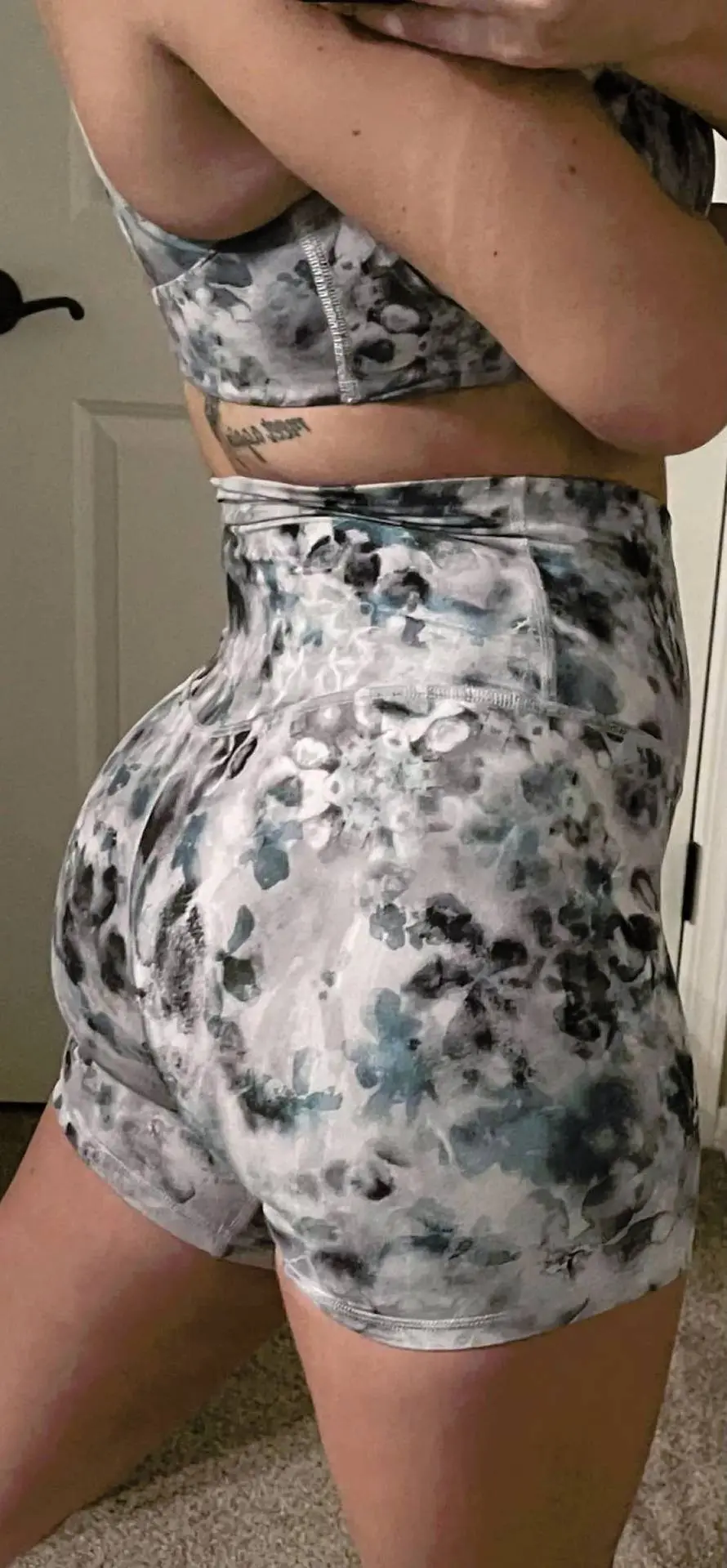 Curvy person in a blue and white marbled print Lululemon sports bra and booty shorts selfie