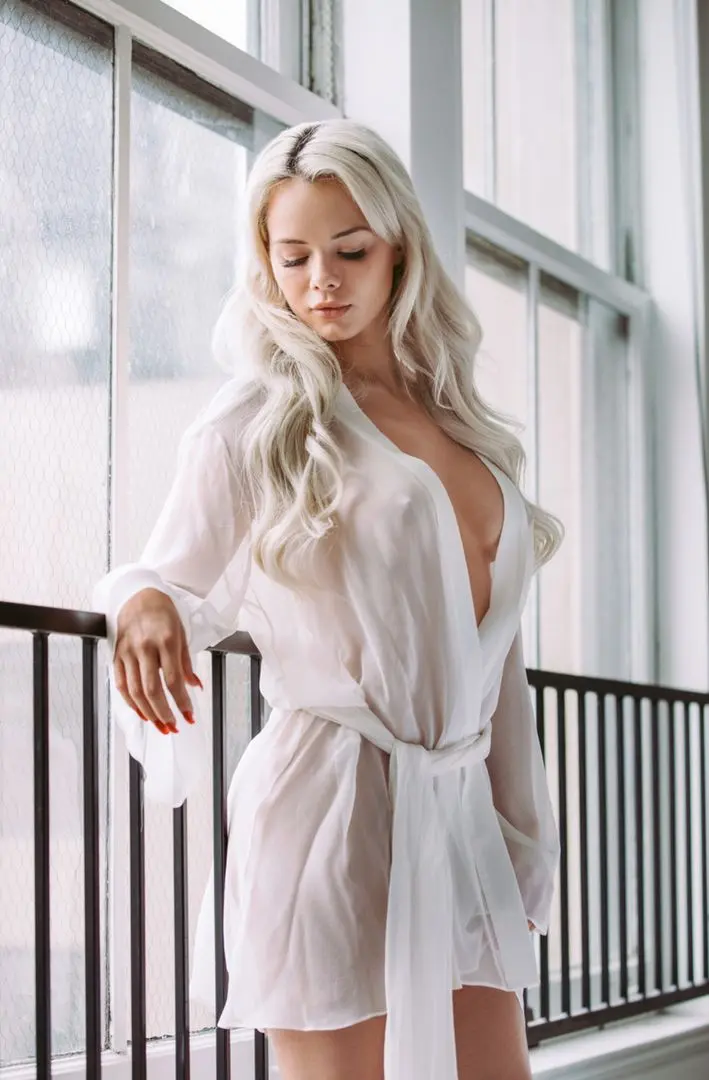 Elsa Jean in a sheer white robe posing by a window