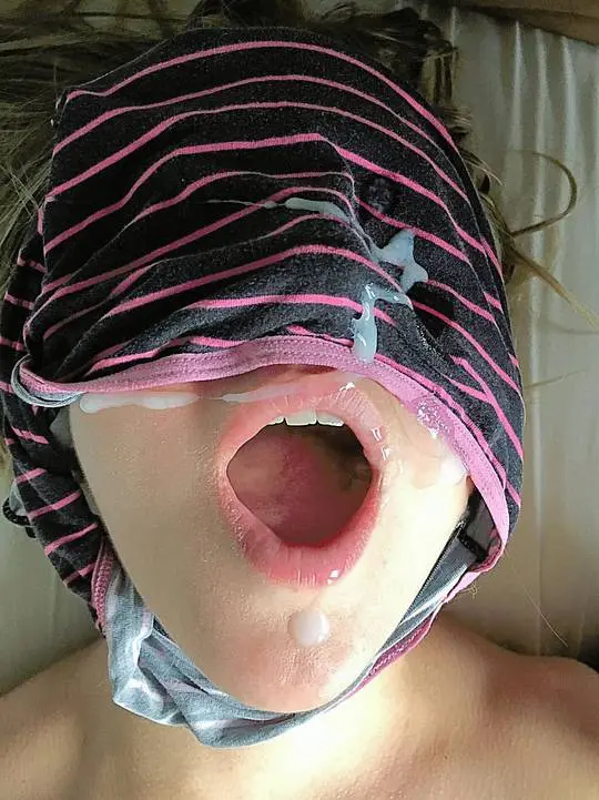 White blonde woman blindfolded with a striped shirt, open mouth, and cum on her face