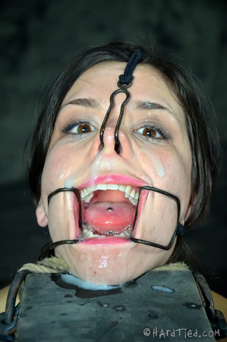 Juliette March nose hooked, mouth spread open, face covered in cum, helplessly staring into the camera