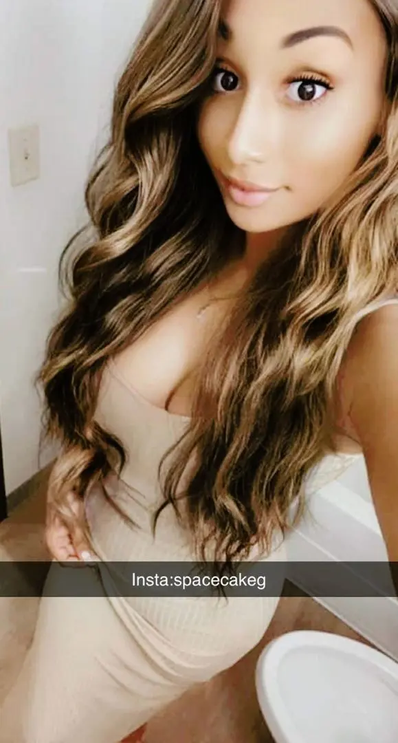 Spacecakeg in a tight beige dress taking a bathroom selfie