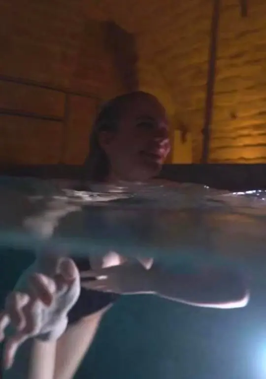 Tepel juultje Tieleman in dark swimwear partially submerged in an indoor swimming pool