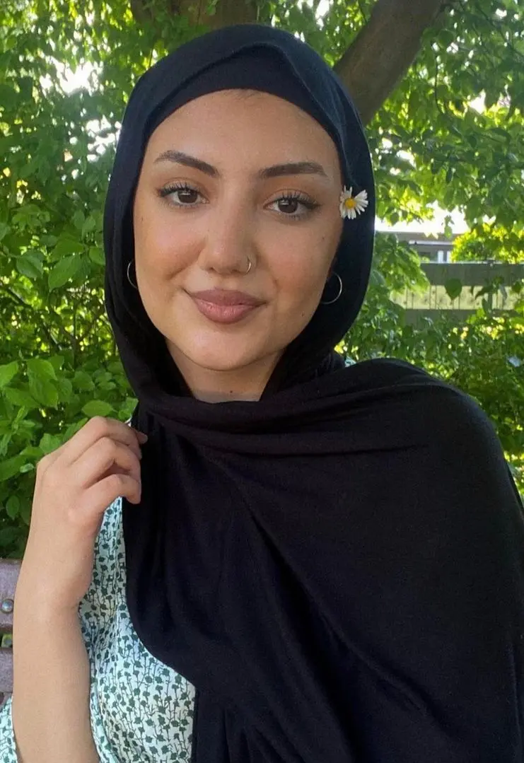 Arab hijabi woman in a floral dress with a nose ring and hoop earrings posing outdoors