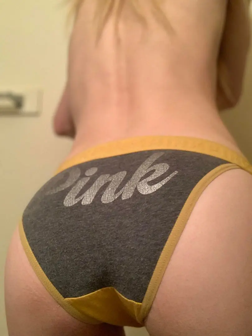 Slim blonde woman in grey and yellow PINK brand fullback panties, back view pelfie showing buttocks