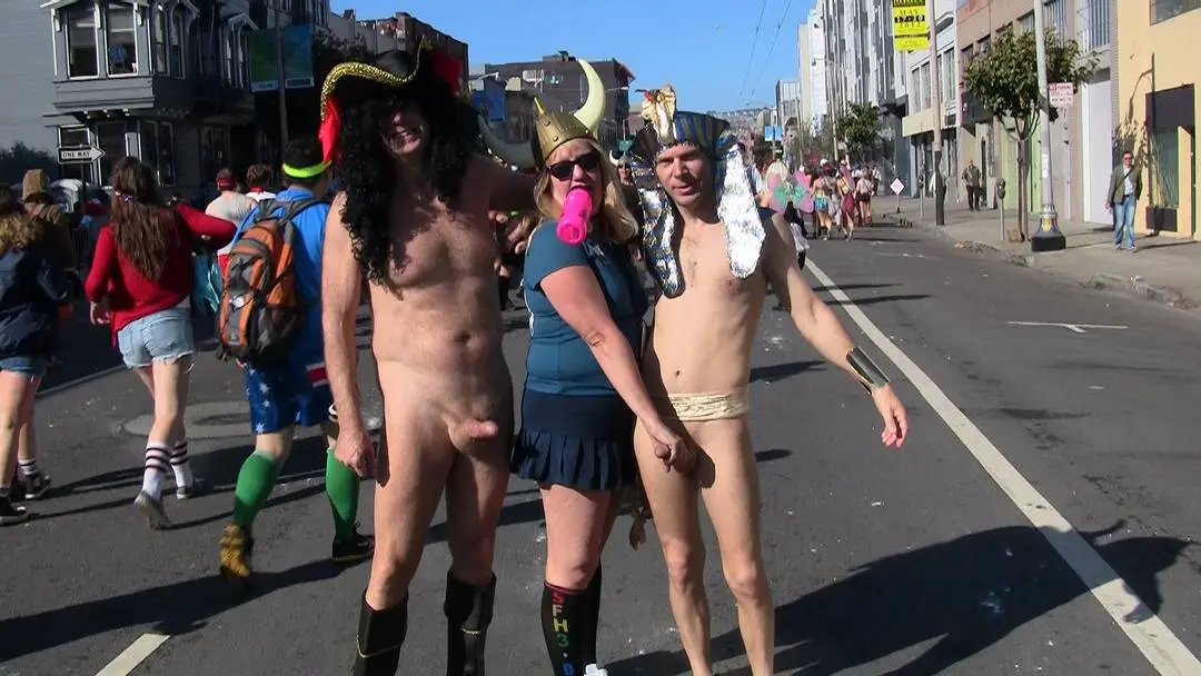 Public CFNM at Bay to Breakers with a man in a pirate hat and a woman in a gold horn hat on a city street.